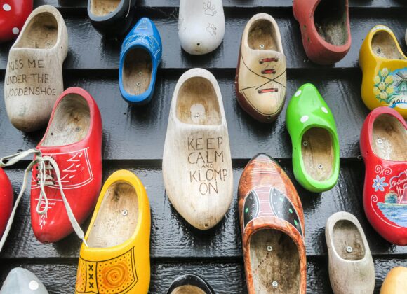 👟 Best Shoes for Ireland: A Complete Guide to Shoes to Wear in Ireland 🇮🇪 A colorful display of wooden clogs on a black wall, featuring various designs and phrases like "KEEP CALM AND KLOMP ON," creating a quirky, vibrant feel