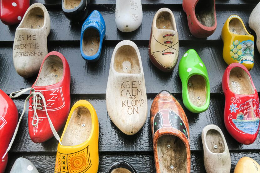 👟 Best Shoes for Ireland: A Complete Guide to Shoes to Wear in Ireland 🇮🇪 A colorful display of wooden clogs on a black wall, featuring various designs and phrases like "KEEP CALM AND KLOMP ON," creating a quirky, vibrant feel