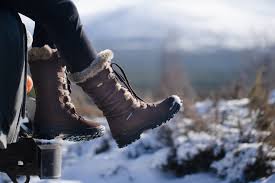 Women's Waterproof Boots for Winter Cozy winter boots with fur lining rest outside a car against a snowy landscape. The scene conveys a sense of adventure and tranquility.