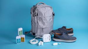 Step-by-Step Packing Guide for Europe: Travel Smart, Pack Right A gray backpack, blue-gray shoes, a USB charger, a power adapter, and labeled containers are neatly arranged on a bright blue background. Modern and organized.