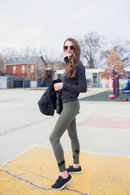 Zella Leggings Review: The Ultimate Guide to Style, Comfort A woman in sunglasses stands outdoors in a casual outfit with a black jacket and green leggings. She's smiling, conveying a relaxed, confident vibe.