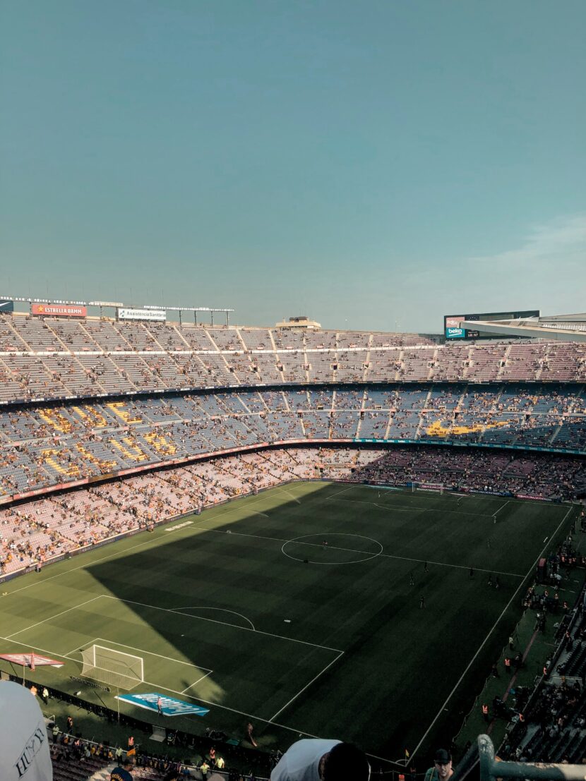 ⚽ FIFA World Cup 2026 Tickets: Your Ultimate Guide to Attending the Biggest Football Event in History Aerial view of a large, filled football stadium under a clear sky. The vibrant green pitch contrasts with rows of multicolored seats and cheering fans.