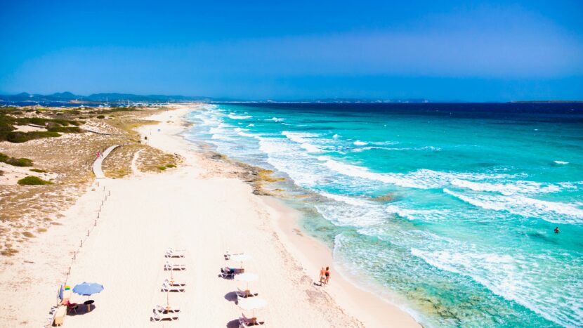 🌴 Beach Vacation Packing List for Mexico: From Inspiration to Reality A sunlit beach with pristine white sand extends towards the horizon, bordered by turquoise waves. Sun loungers and umbrellas create a relaxing, serene atmosphere.