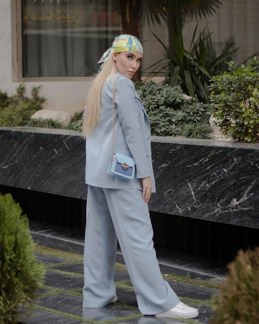 đ§ď¸ Introduction: Fashion Meets Function in the Blondo Villa Bootie A person in a light blue suit and white sneakers stands outside. They wear a colorful headscarf and carry a matching light blue purse, exuding confidence.