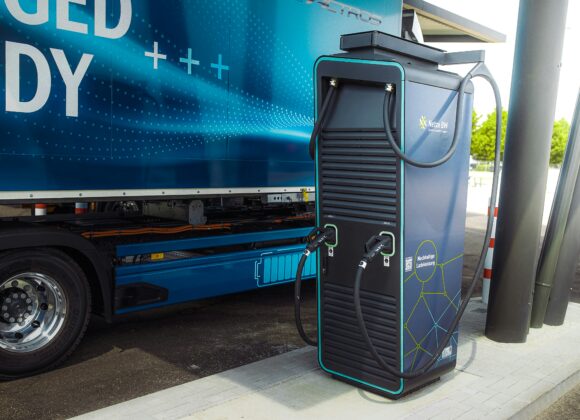 The Best Dual Voltage Travel Clothes Steamer of 2025 ✈️✨ Electric charging station with cables beside a blue electric truck reading "CHARGED READY." Modern technology, clean energy emphasis.