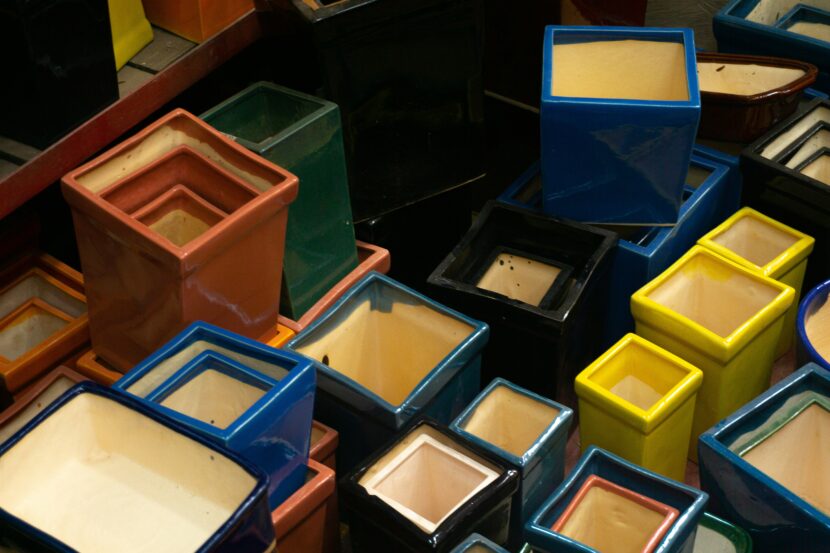 A collection of colorful, glossy, square-shaped ceramic pots stacked together. They vary in size and include hues such as red, blue, green, and yellow.