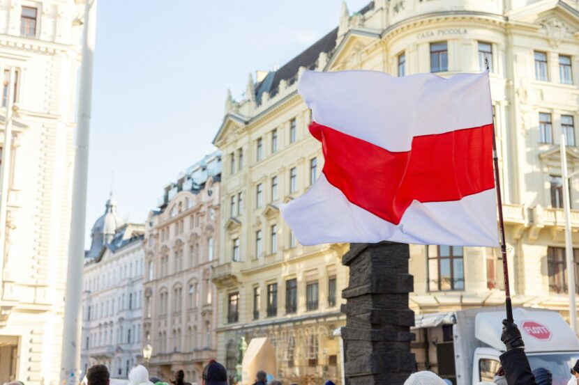 Poland–Russia Relations in 2025: Tensions, Drones, and the NATO Dilemma White-red-white flag waved in a city square, surrounded by historic European buildings under a clear sky. Creates a feeling of unity and protest