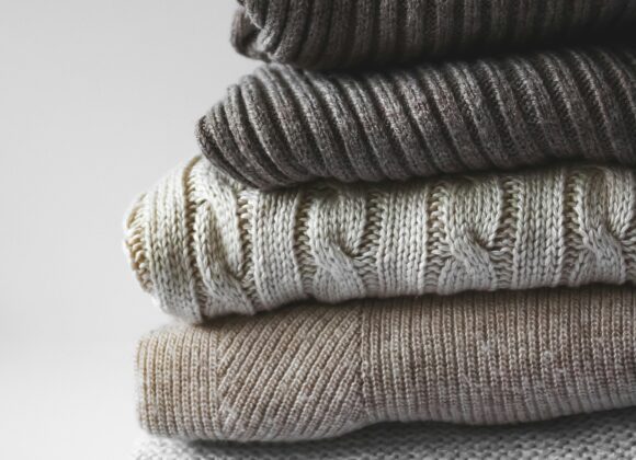 ๐งต Best Alternative to Merino Wool: Discovering the Ideal Merino Wool Alternative for Every Lifestyle A stack of four folded sweaters in neutral tones with varying knit textures, including ribbed and cable patterns. The atmosphere is cozy and inviting.