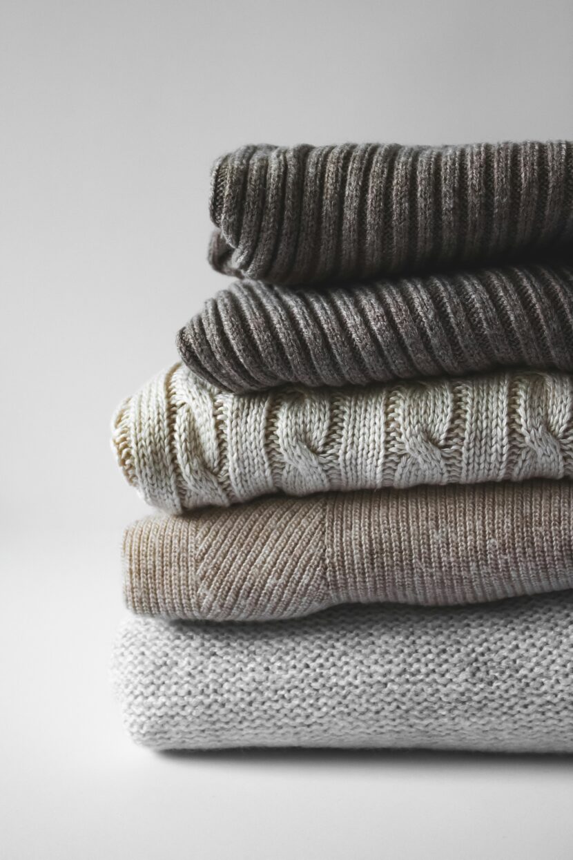 š§µ Best Alternative to Merino Wool: Discovering the Ideal Merino Wool Alternative for Every Lifestyle A stack of four folded sweaters in neutral tones with varying knit textures, including ribbed and cable patterns. The atmosphere is cozy and inviting.