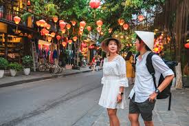 What to Wear in Vietnam Two people walk down a lantern-lit street in a vibrant, festive atmosphere. They wear casual summer clothes and hats, conveying a sense of wanderlust and joy.