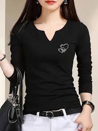 Women's Long Sleeve T-Shirts Woman in a black long-sleeve top with heart design, wearing white pants and black belt. She holds a black bag, conveying a stylish, elegant look.